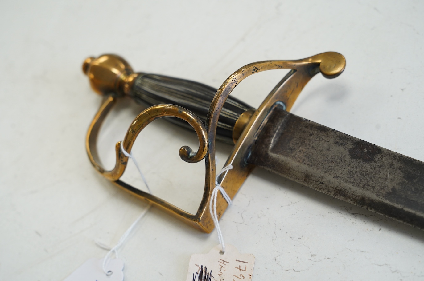 An English officer’s hanger, c.1800. brass grip with scrolling side bar, fluted ebony grip, blade 74.5cm. Condition - fair, guard significantly altered